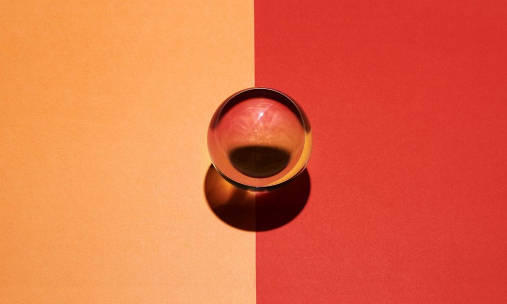 Glass sphere on a divided orange and red background placed in the center over the dividing line with internal blend of color